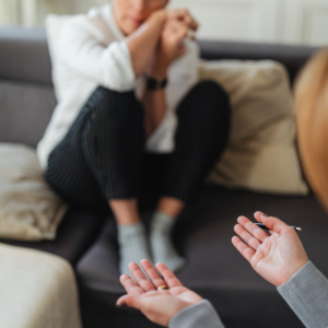 "Personne recroquevillée sur un canapé, mains tendues en signe de soutien lors d'un accompagnement du traumatisme à Savenay"